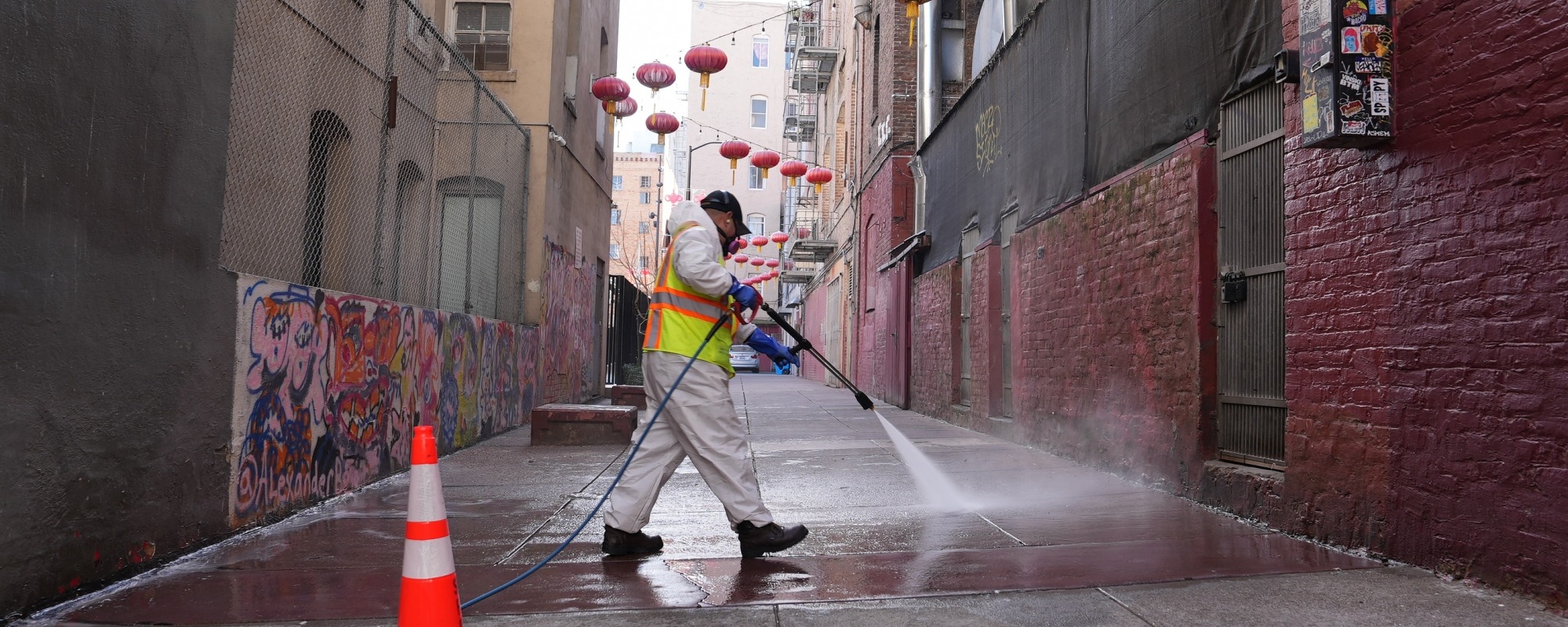 Cleaning crew member steam cleaning an alleyway in Chinatown
