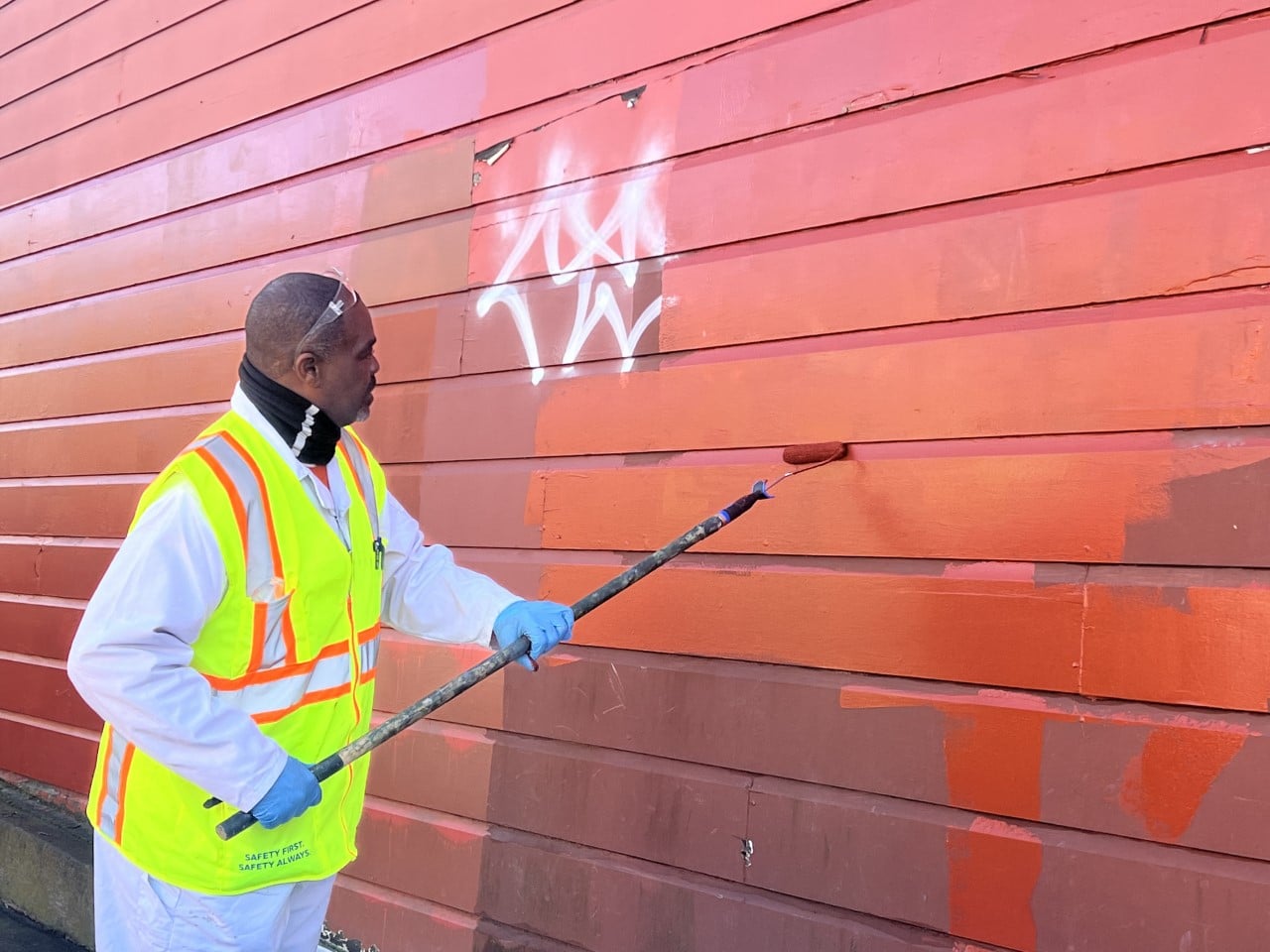 A person painting over graffitti