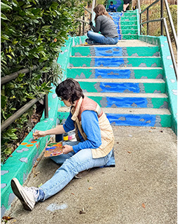 woman painting a staircase mural