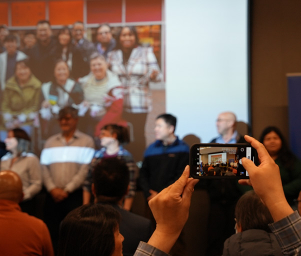 employees lining up against the wall to be recognized. A photographer in the front is capturing their moment.