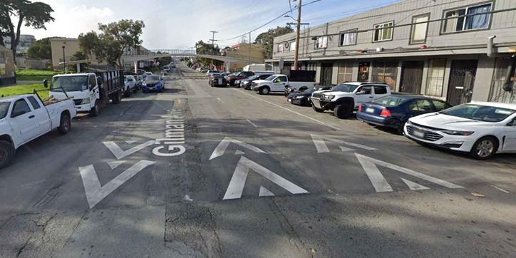 Street level view photograph of Gilman Avenue roadway showing speed bumps, vehicles parked on both sides of the street.
