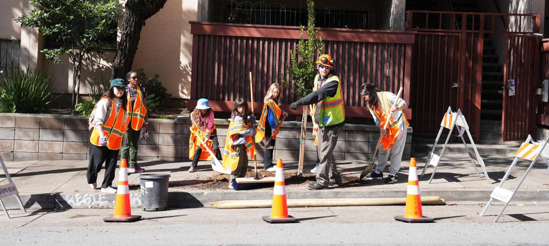 an arborist works with a group of young volunteers to plant trees